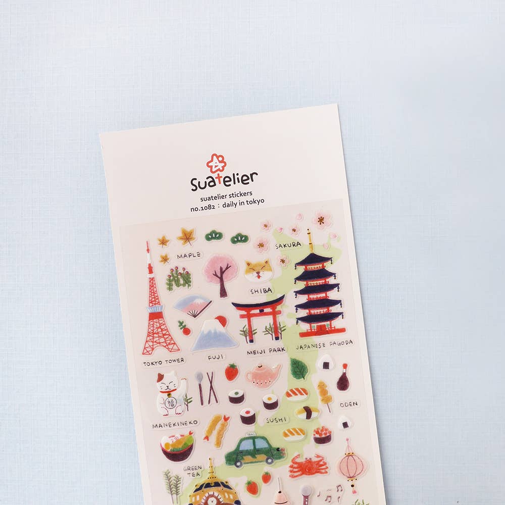 Sheet of illustrated stickers with various designs on a light blue background, featuring the brand 'Suatelier'.